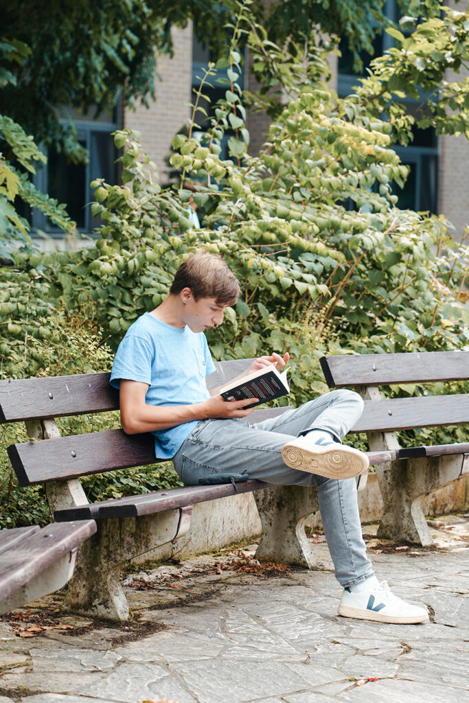 Jongen leest een boek op een bank