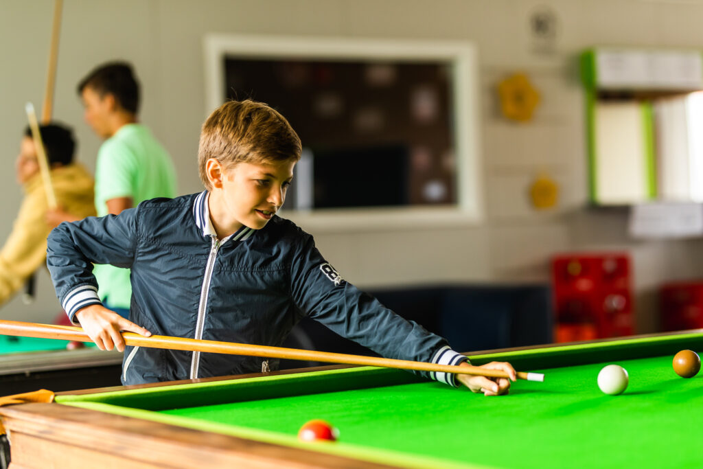 Jongen die aan de pooltafel staat